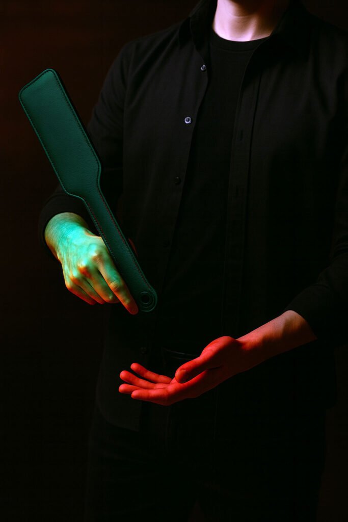 Persona adulta vestida de oscuro mostrando la técnica de muñeca con un accesorio en un estudio con luz tenue